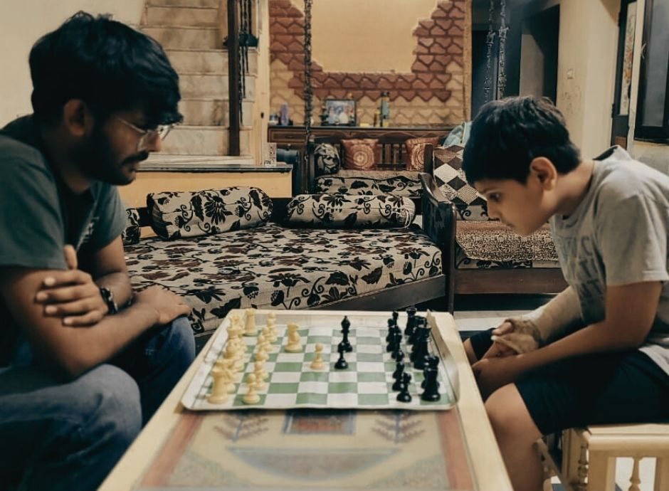Two people at a chessboard, one watching it closely