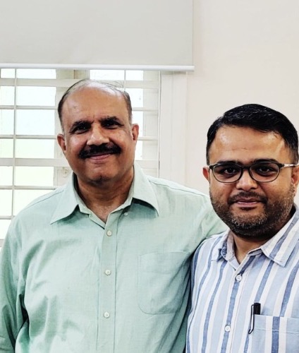 Two men standing side by side, smiling at the camera