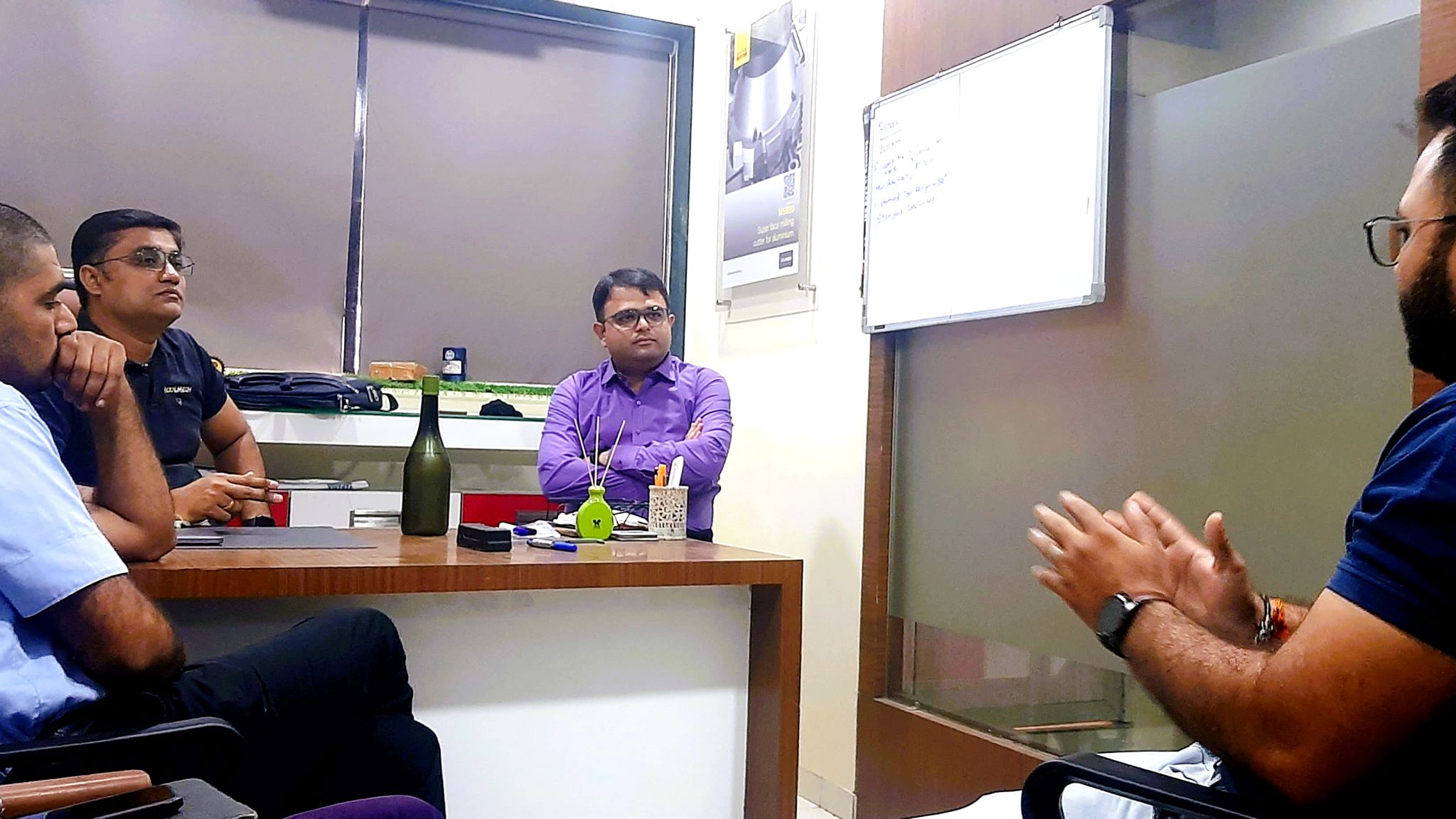 A team meeting around a table in an office, with one person speaking