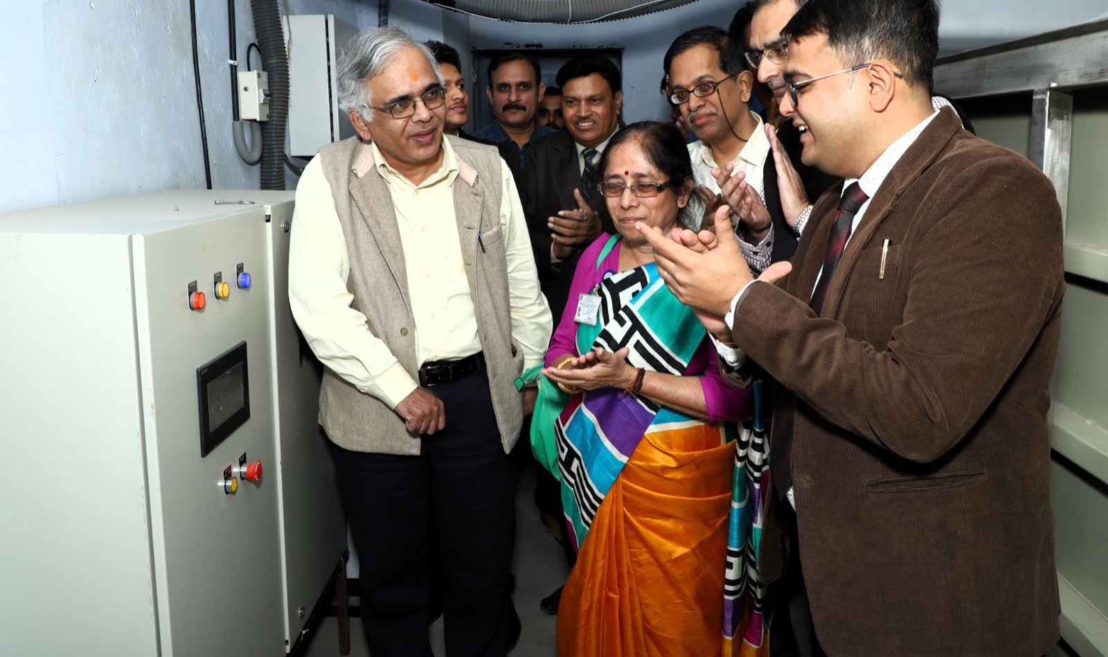 A group applauding beside an equipment panel at the opening of a manufacturing unit