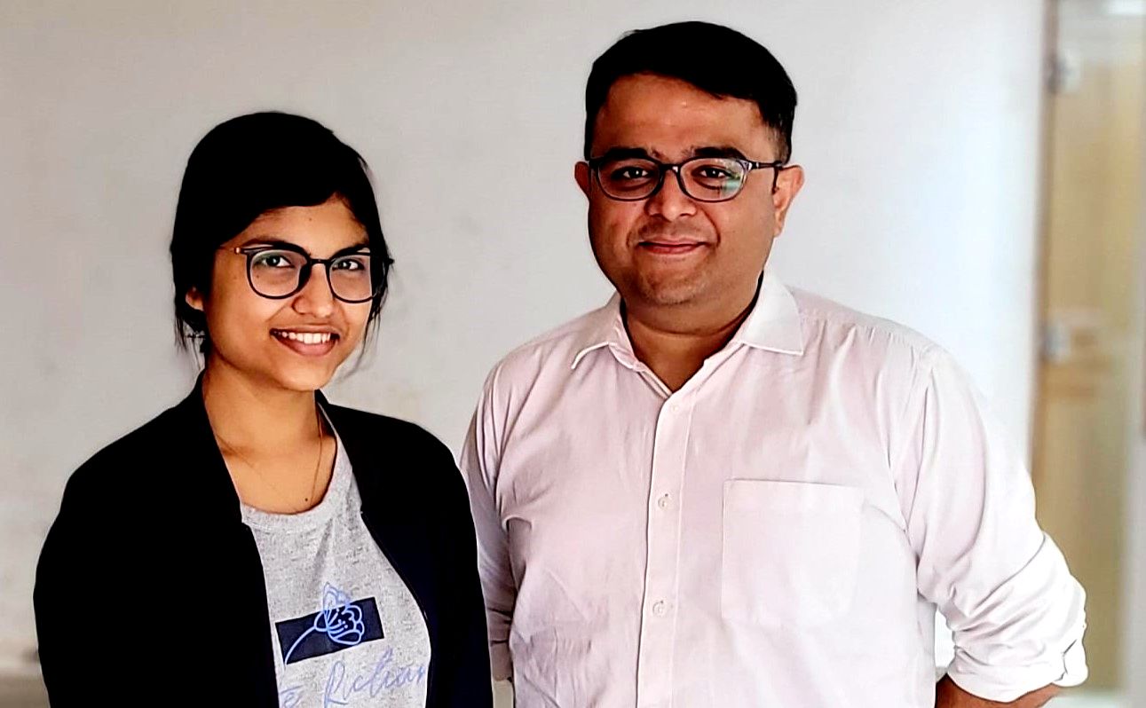 Two people standing side by side, smiling at the camera